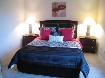 a bedroom with a large bed with red and blue pillows at Family Vacation Home With Pool and Spa Near Disney and Universal in Orlando