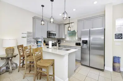 a kitchen with white cabinets and a stainless steel refrigerator at Seas The Day Cottage Near Disney With Margaritaville Resort & Island H2O Access - 8001Ff in Orlando