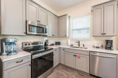 a kitchen with white cabinets and stainless steel appliances at Tropical Paradise Cottage Near Disney With Margaritaville Resort & Island H2O Access - 8061Kd in Orlando