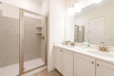 a white bathroom with two sinks and a shower at A Wave From It All Cottage With Private Pool Near Disney And Margaritaville Resort & Island H2O Access - 8039Su in Orlando