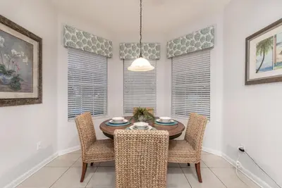 a dining room with a table and chairs and windows at Spacious Home wPrivate PoolSpa & FREE Waterpark in Orlando
