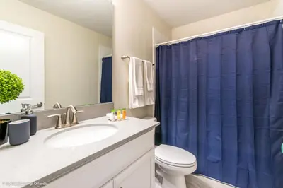 a bathroom with a toilet and a blue shower curtain at 2911 Fable Street in Kissimmee