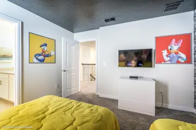 a bedroom with a yellow bed and paintings on the wall at 2911 Fable Street in Kissimmee