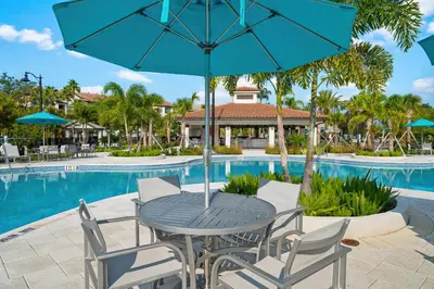 a table and chairs with an umbrella next to a pool at First floor Vista Cay Condo wFREE Resort Access in Orlando