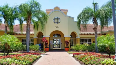 a building with palm trees and flowers in front of it at Breakview Fun & Sun in Orlando