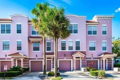 a pink building with palm trees in front of it at Updated Vista Cay Townhome, 10 min from Universal in Orlando