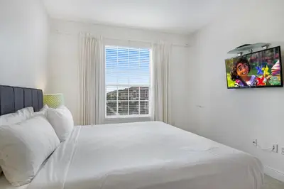 a white bedroom with a large bed and a window at Updated Condo Near Conv Ctr, I-Drive & Universal in Orlando
