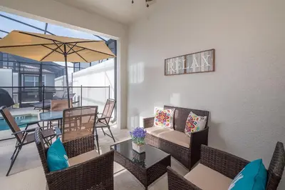 a living room with a table and chairs and an umbrella at 4834BV TOWNHOUSE 4 BEDROOMS & 3 BATHROOMS + POOL in Kissimmee