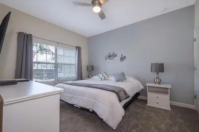 a white bedroom with a bed and a window at 4834BV TOWNHOUSE 4 BEDROOMS & 3 BATHROOMS + POOL in Kissimmee