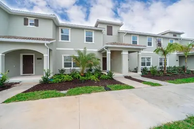 a large white house with palm trees at 4830FA TOWNHOUSE 4 BEDROOMS & 3 BATHROOMS + POOL in Kissimmee