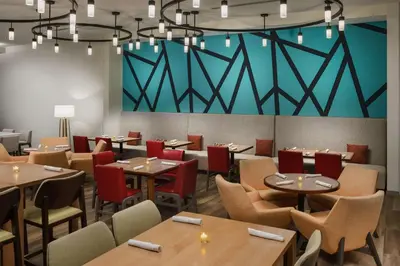 a dining room with tables and chairs and a large wall at Hilton Garden Inn Apopka City Center, Fl in Orlando