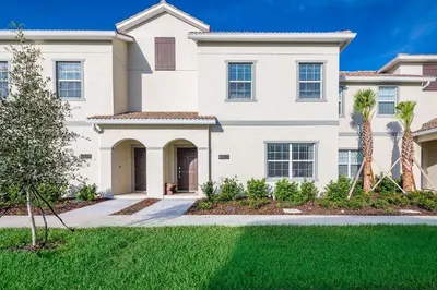 a large white house with palm trees in front of it at 4929GC TOWNHOUSE 4 BEDROOMS & 3 BATHROOMS + POOL in Kissimmee