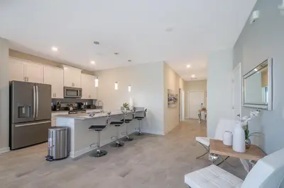 a kitchen with bar stools and a kitchen with a refrigerator at 4975AN TOWNHOUSE 5 BEDROOMS & 4 BATHROOMS + POOL in Kissimmee
