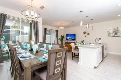 a dining room and living room with a table and chairs at Luxurious Décor 4 Bd w/ Pool Close to Disney 4820 in Kissimmee
