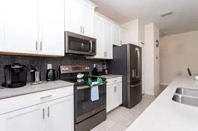 a kitchen with white cabinets and a black refrigerator at Luxurious Décor 4 Bd w/ Pool Close to Disney 4820 in Kissimmee