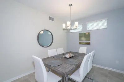 a dining room with a wooden table and white chairs at 4721-101FG STOREY LAKE, CONDO 3/2 GARDEN VIEW in Kissimmee
