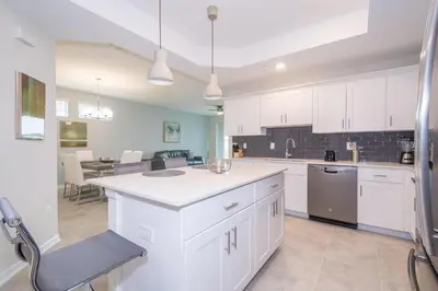 a large kitchen with white cabinets and a dining room at 4721-101FG STOREY LAKE, CONDO 3/2 GARDEN VIEW in Kissimmee