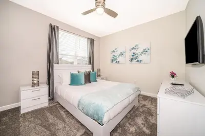 a white bedroom with a bed and a tv at 2770AG VILLA 5 BED/5 BA (SANITIZED) in Kissimmee