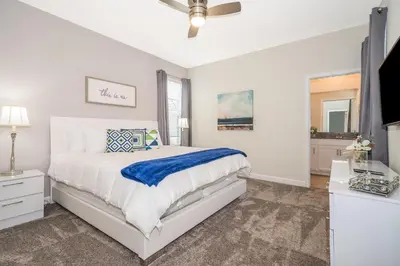 a white bedroom with a bed and a tv at 2770AG VILLA 5 BED/5 BA (SANITIZED) in Kissimmee