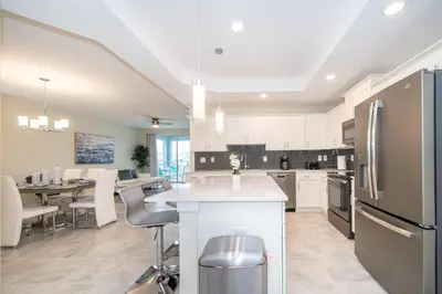 a kitchen with white cabinets and a table with chairs at 3120-201BB STOREY LAKE, CONDO 3/2 GARDEN VIEW in Kissimmee