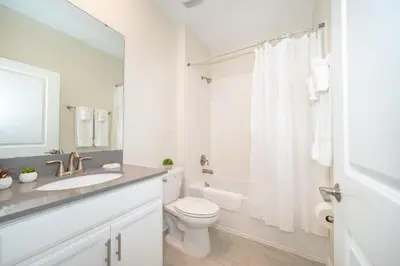 a white bathroom with a toilet and a sink at 2731EE VILLA 5 BED/5 BA (SANITIZED) in Kissimmee