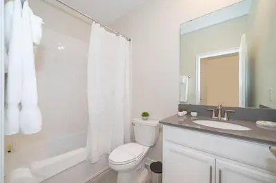 a white bathroom with a toilet and a sink at 2731EE VILLA 5 BED/5 BA (SANITIZED) in Kissimmee