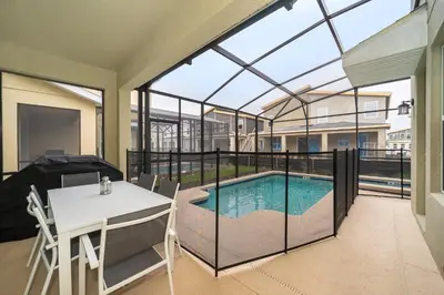 a house with a swimming pool and a white table and chairs at 2744HM VILLA 5 BED/5 BA (SANITIZED) in Kissimmee