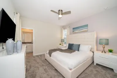 a white bedroom with a bed and a flat screen tv at 2744HM VILLA 5 BED/5 BA (SANITIZED) in Kissimmee