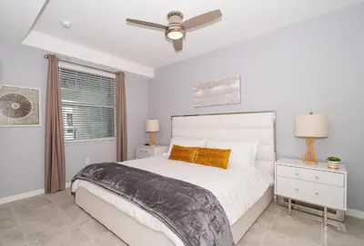 a white bedroom with a bed and a ceiling fan at 3111-302HM STOREY LAKE, CONDO 2/2 LAKE VIEW in Kissimmee