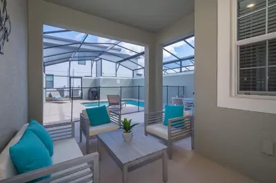 a patio with blue pillows and a table and chairs at 4964RS TOWNHOUSE 4 BEDROOMS & 3 BATHROOMS + POOL in Kissimmee