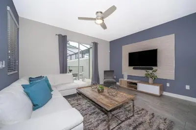 a living room with a white couch and a flat screen tv at 4964RS TOWNHOUSE 4 BEDROOMS & 3 BATHROOMS + POOL in Kissimmee