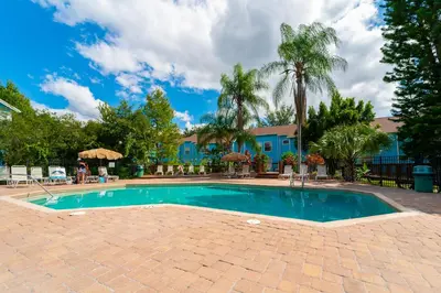 a swimming pool with a brick patio and palm trees at VOS-2739PB-73 - Somerset Gardens (S) in Kissimmee
