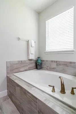 a large white tub in a bathroom with a window at Upscale Modern Getaway home with heated pool/hot tub, 9 beds 8.5 bath Sleeps 18+ in Orlando