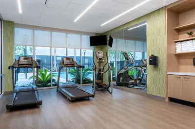 a gym with three tread machines in a room at TRYP by Wyndham Orlando in Orlando