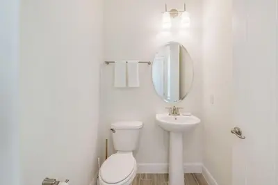 a white bathroom with a toilet and a sink at Sanderella Castle! Premium Cottage With Private Hot Tub Near Disney With Margaritaville Resort & Island H2O Access - 3037Sp in Orlando