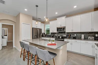 a kitchen with white cabinets and a island with bar stools at Storey Lake Resort 5 Bedroom Vacation Home with Pool 2307 in Kissimmee