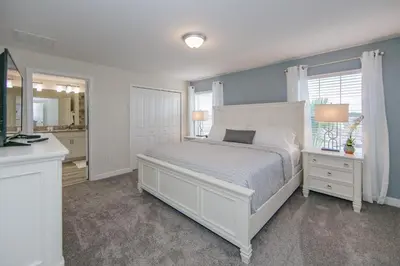 a bedroom with a white bed and a mirror at 4907JA TOWNHOUSE 4 BEDROOMS & 3 BATHROOMS + POOL in Kissimmee