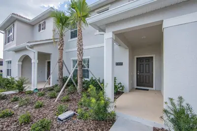 a white house with palm trees in front of it at 4907JA TOWNHOUSE 4 BEDROOMS & 3 BATHROOMS + POOL in Kissimmee
