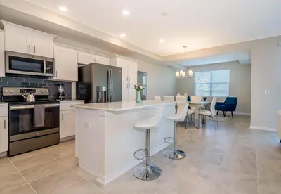 a kitchen with white cabinets and a table and chairs at 4731-206OR STOREY LAKE, CONDO 2/2 GARDEN VIEW in Kissimmee