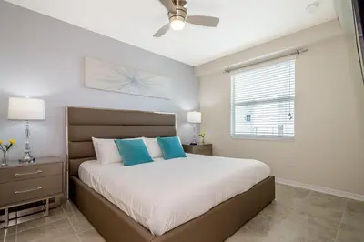 a bedroom with a bed with blue pillows and a window at 4731-206OR STOREY LAKE, CONDO 2/2 GARDEN VIEW in Kissimmee