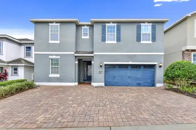a gray house with a brick driveway at Amazing Home With Theme Rooms, Game Rooms Near Disney With Waterpark & Resort Access At Encore Resort - 7647Wl in Kissimmee