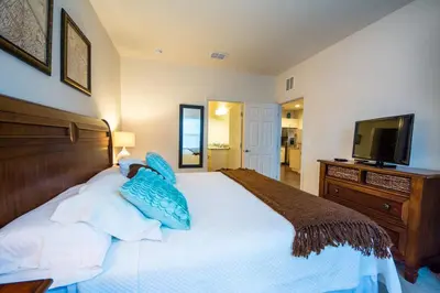 a bedroom with a bed with blue pillows and a television at HAPPY PORT, your home very close to entertainment in Kissimmee