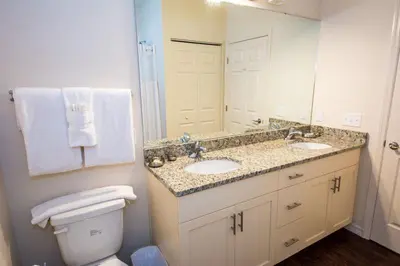 a bathroom with two sinks and a toilet and a mirror at HAPPY PORT, your home very close to entertainment in Kissimmee