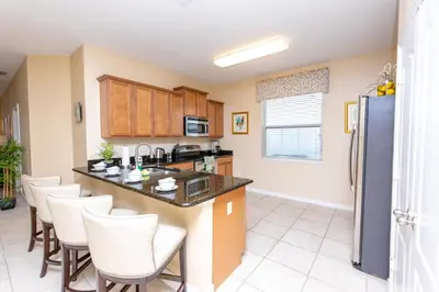 a kitchen with a large island with white chairs at Newly Remodeled 1 story - 5 Bed 5 Bath with Pvt Pool Spa And Game Room in Kissimmee