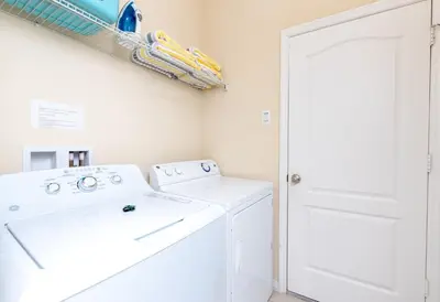 a white laundry room with a washer and dryer at Newly Remodeled 1 story - 5 Bed 5 Bath with Pvt Pool Spa And Game Room in Kissimmee