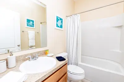 a bathroom with a sink and a toilet and a tub at Newly Remodeled 1 story - 5 Bed 5 Bath with Pvt Pool Spa And Game Room in Kissimmee