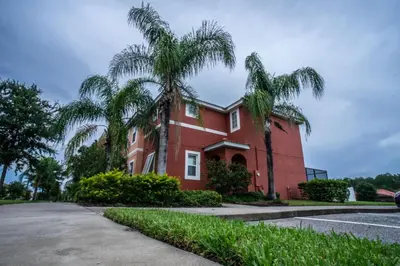 a red house with palm trees in front of it at Fantastic 4br 3ba with Pvt Pool near to Disney in Kissimmee