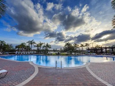 a large swimming pool with palm trees and a cloudy sky at 205 - Disney, Universal, Convention Center in Orlando