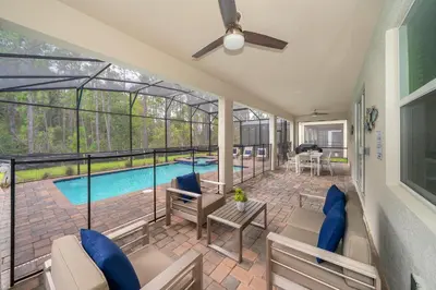 a screened in porch with a pool and a ceiling fan at 2705JT LUXURY 7 BED/5 BA (SANITIZED) in Kissimmee