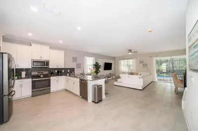 a large kitchen with white cabinets and a living room at 2705JT LUXURY 7 BED/5 BA (SANITIZED) in Kissimmee